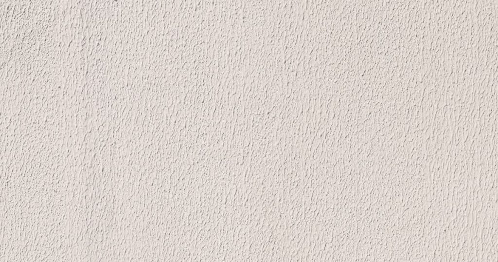 Detailbeeld van een gevel bekleed met crepi in gebroken wit.