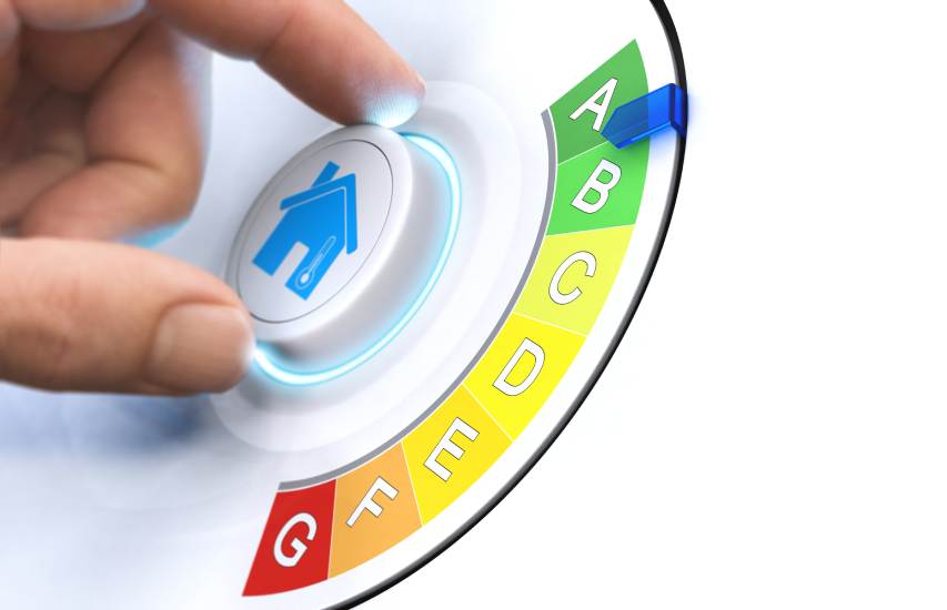 Verschillende energielabels: iemand draait aan een witte knop met een huis met thermometer op. Bepaalt hij zo het energielabel van zijn woonst? De blauwe pijl staat op A.