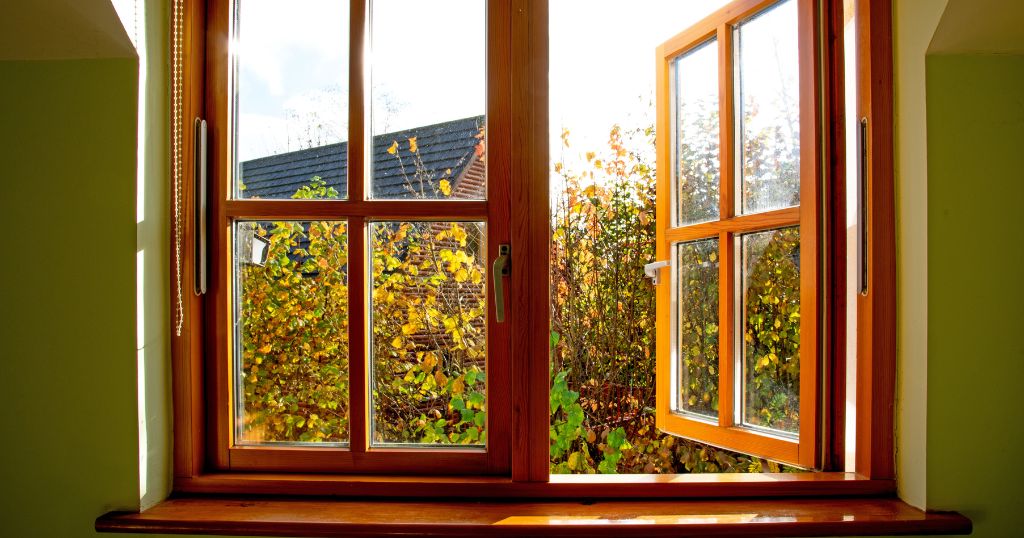 Een houten raam met uitzicht op bomen.