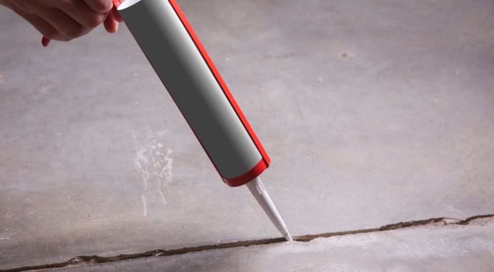 Er wordt een kit/seal aangebracht in een scheur in de vloer.