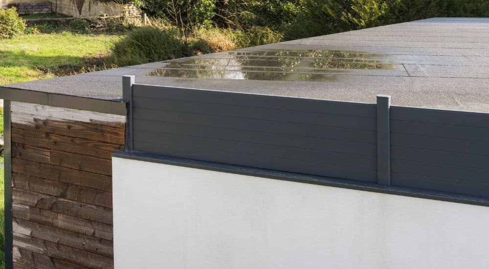 Lekkage op een plat dak. Er ligt een plas water op het dak. 