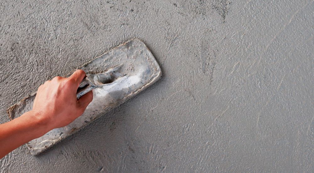 Een specialist brengt grijze beton ciré aan op een muur. 