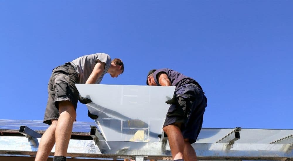 Twee mannen leggen raamwerken aan bovenop de aanbouw