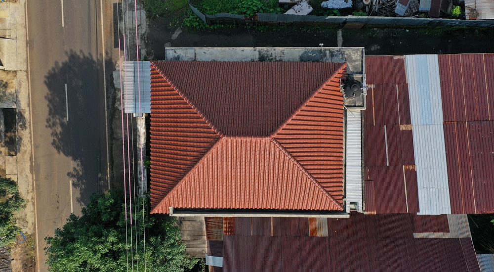 Bovenaanzicht van een schild dakbedekking van een woning langs een drukke baan.