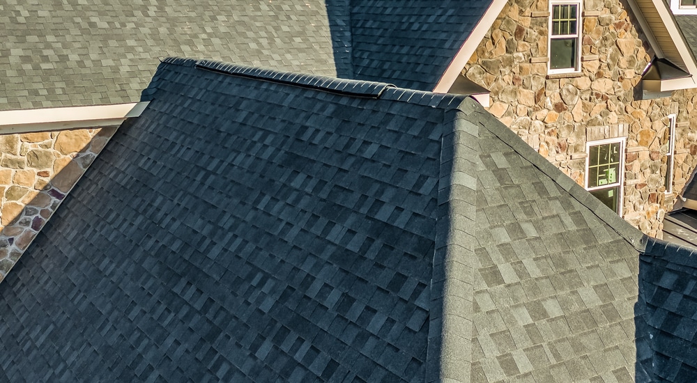 Detailbeeld van een leien schilddak van een oudere woning met ruwe stenen als gevelbekleding.