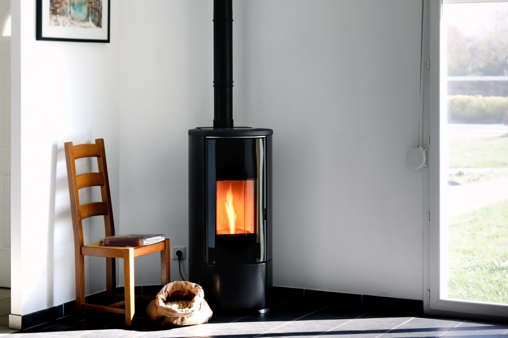 Een kachel in een serre als verwarming. Naast de kachel is een houten serre te zien.