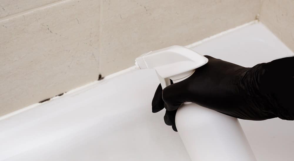 Schimmelaanslag wordt behandeld met een schimmelspray in de badkamer