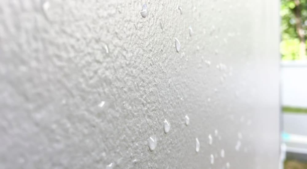 Muur behandeld met vochtwerende verf, met druppels vocht op het oppervlak