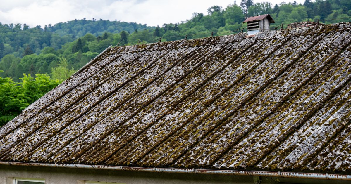 Oude asbesthoudende golfplaten op het dak van een woning.