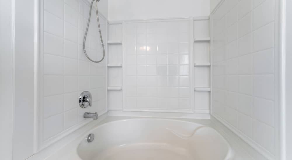 Een wit betegelde bad douchecombinatie. 