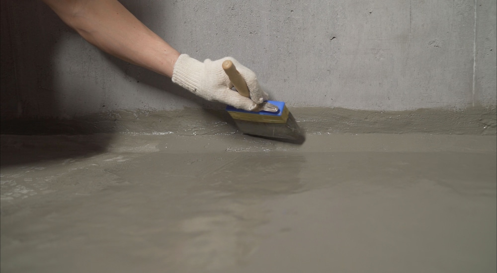 De kimnaad bij een keldervloer wordt afgedicht met een kwast en coating