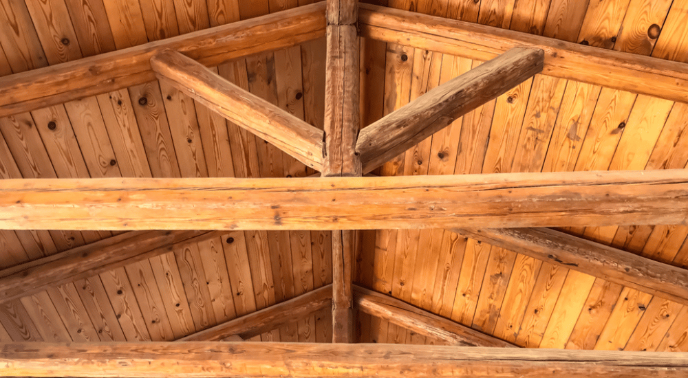 Een hellend dak met zware stevige balken die een gordingendak en het fundament van de rest van de houten dakstructuur vormen. 