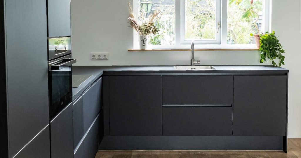 Een zwarte, moderne keuken in L-vorm.