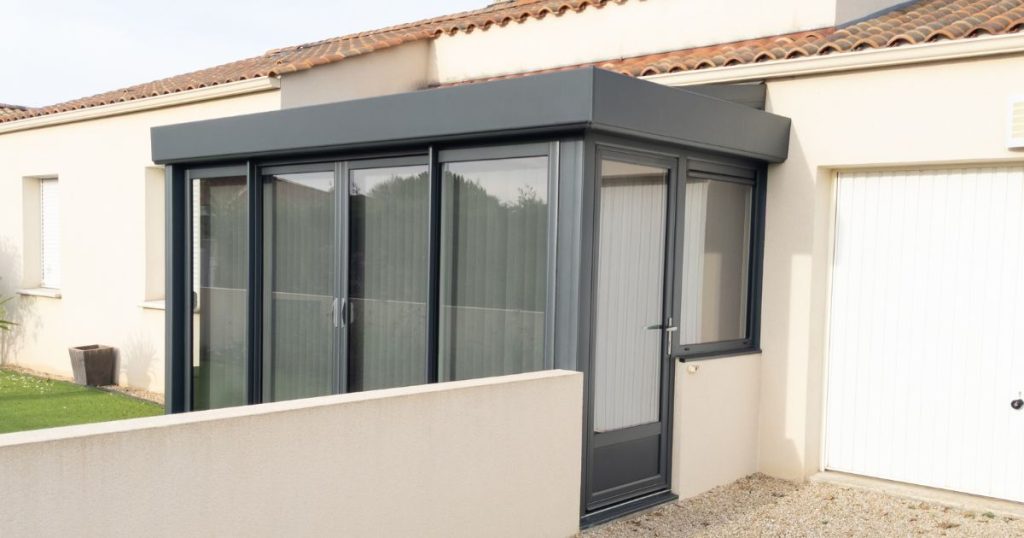 Kleine grijze pvc serre aan een woning