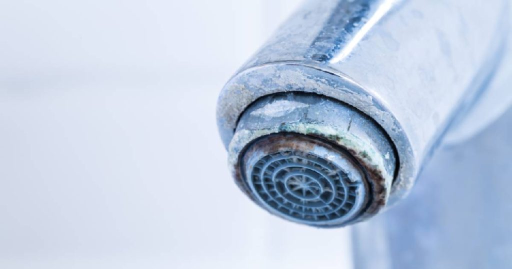 Close-up van een perlator van een kraan met kalkaanslag.