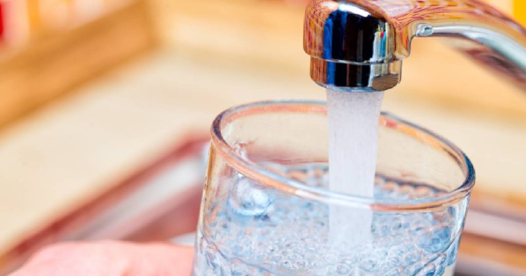 Een nette, glanzende kraan zonder kalk waaruit helder, bacterievrij water stroomt.