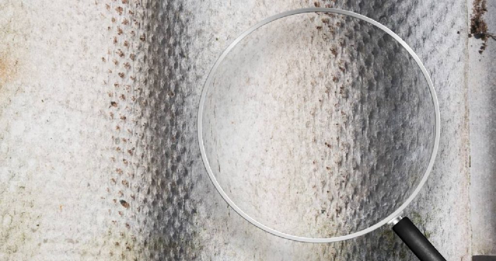 Een vergrootglas boven een asbestplaat in het onderdak van een woning.