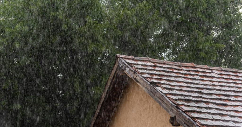 Een dak met dakpannen en stevig onderdak in de regen. Het onderdak beschermt de woning tegen vocht en wind.