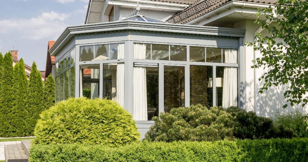 Buitenkant van een orangerie aanbouw met kenmerkende lange, smalle ramen en opstaand koepeldak.