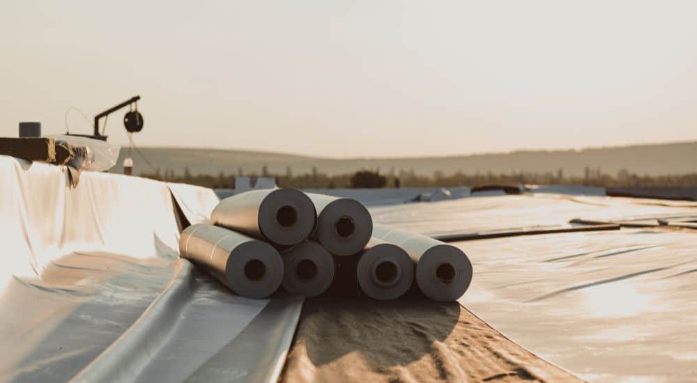 Pvc rollen liggen klaar op een plat dak om uitgerold en gelijmd of gelast te worden.
