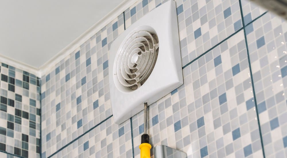 Een mechanisch ventilatierooster wordt geschroefd in de badkamer