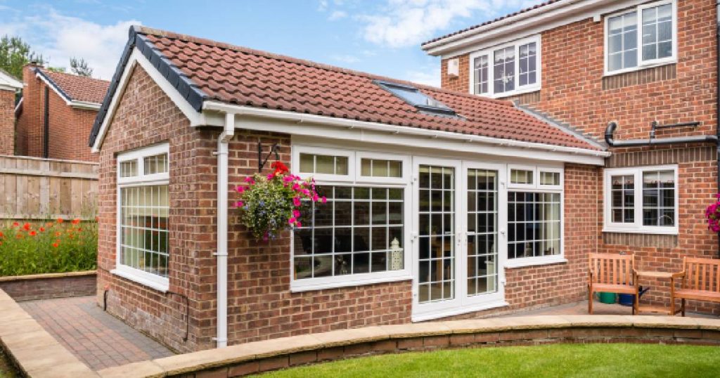 Een perfect geïsoleerde veranda uit steen met grote raampartijen uit hoogrendementsglas, een dak met dakpannen en een lichtkoepel, en geïsoleerde stenen wanden.