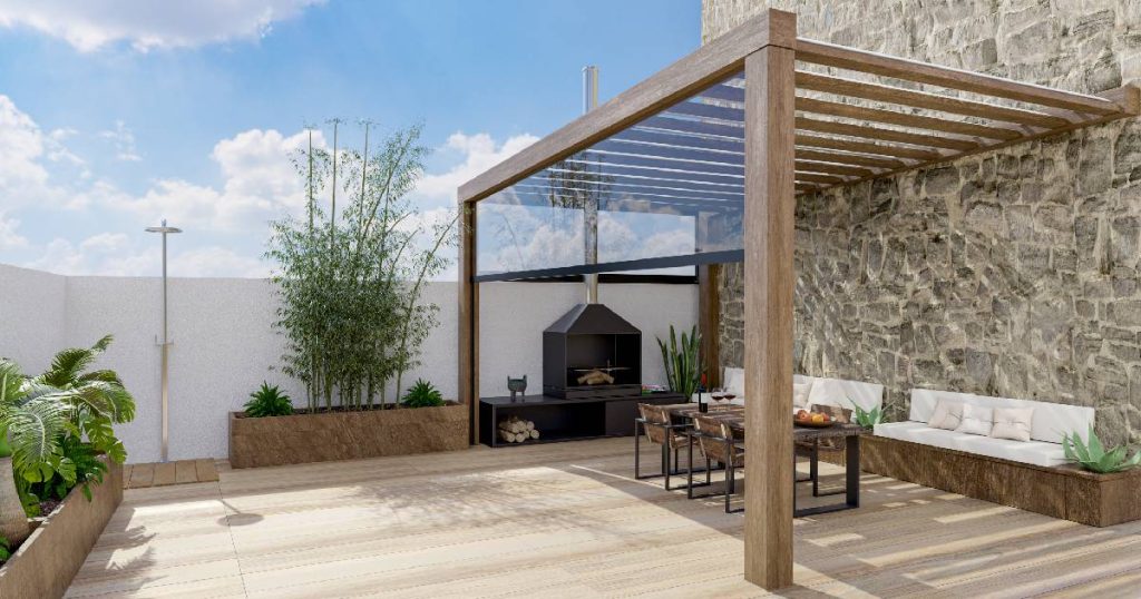 Een moderne pergola tegen de gevel van een woning in een tuin op houten vloer. Onder de pergola staat een zwarte tafel met stoelen. Tegen de gevel onder de veranda staat een ingebouwde houten bank met witte kussens.