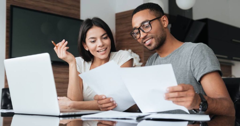 Een jong koppel vergelijkt samen offertes voor een nieuwe serre.