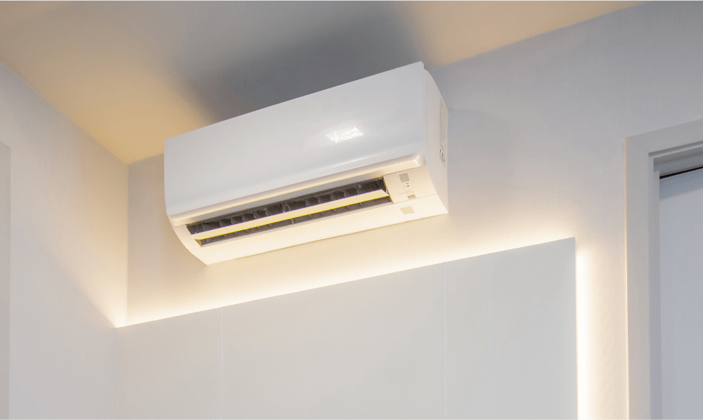 een binnenunit van een aircosysteem aan een witte muur bevestigd.