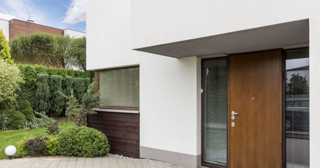 Voorgevel in crepi met houten details en houten voordeur
