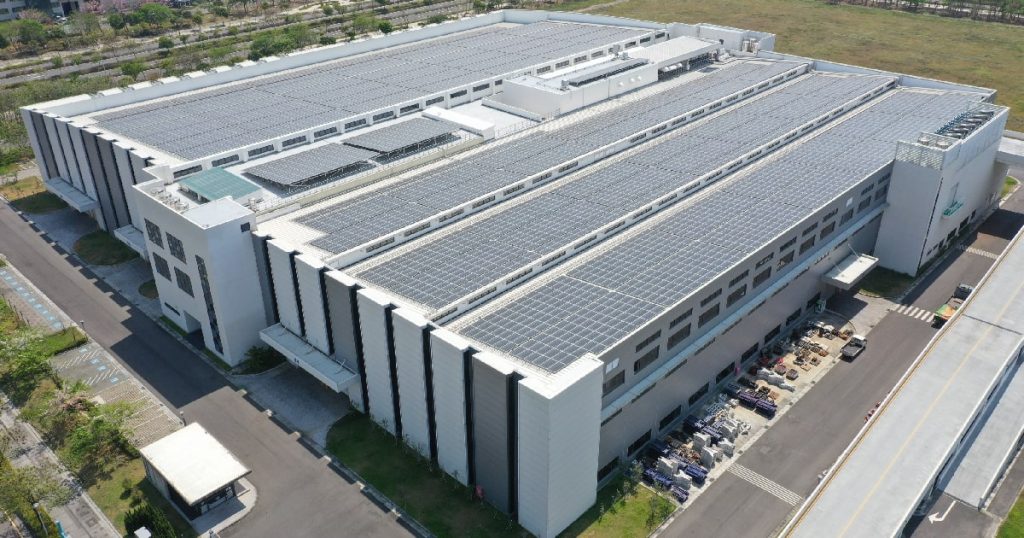Een groot fabrieksgebouw waarvan het dak volledig werd belegd met zonnepanelen.