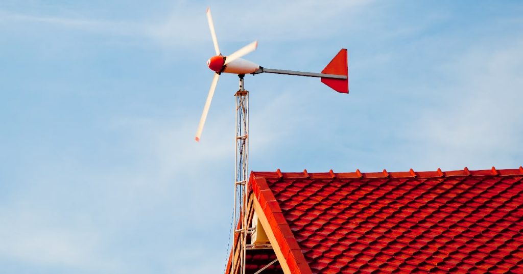 Een rood dak met een kleine, wit met rode windturbine die hernieuwbare energie opwekt.