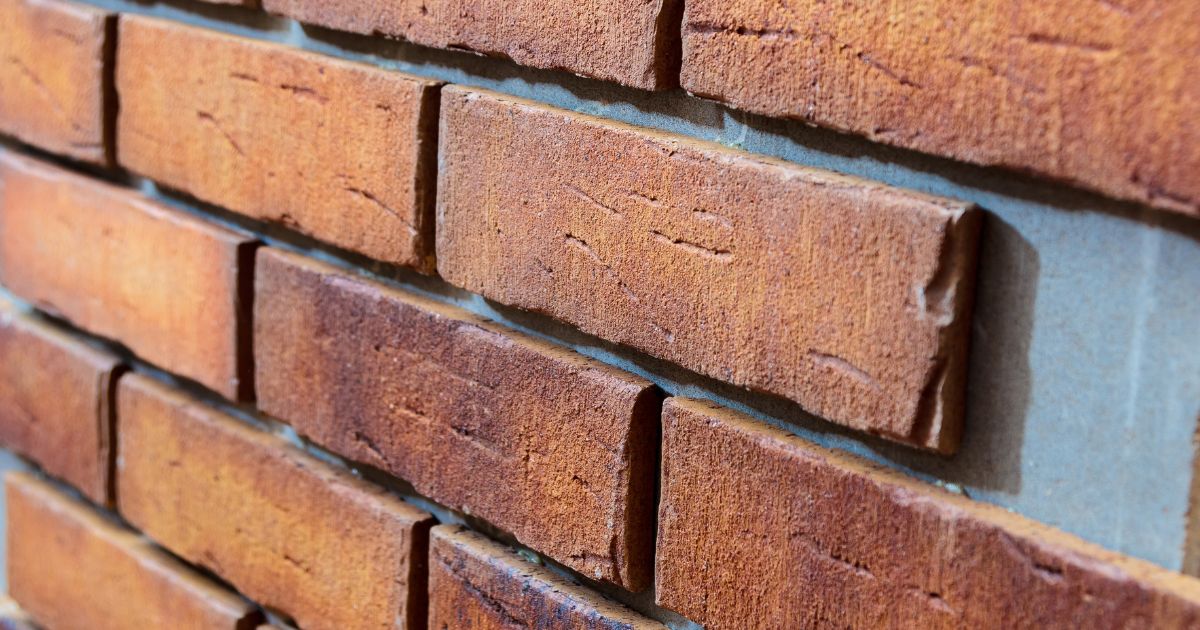 Close-up van baksteenstrips die zorgvuldig zijn aangebracht tijdens het steenstrips plaatsen voor een authentieke baksteenlook.