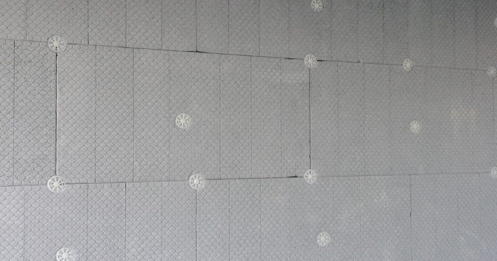 Grijswitte platen van PIR-dakisolatie zijn in tegelverband op een vloer gemonteerd.