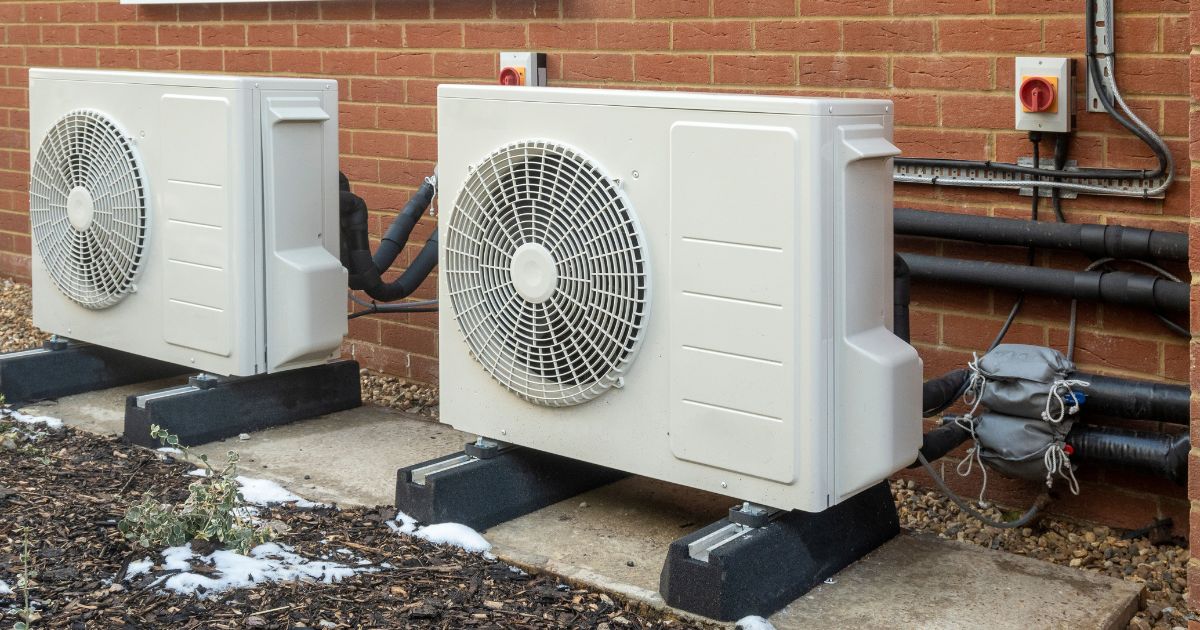 twee buitenunits van warmtepompen die voor een bakstenen muur is geplaatst