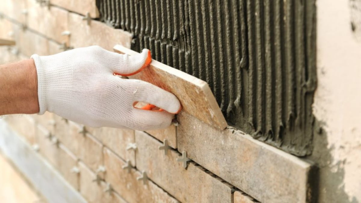 Een specialist plaatst steenstrips op een gevel. 