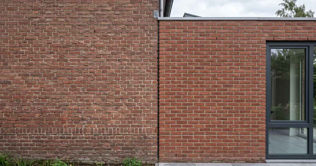 Aanbouw met steenstrips in hetzelfde formaat en dezelfde kleur als het bestaande metselwerk, met doorlopende lagen