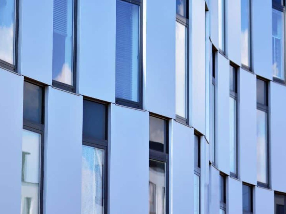 Gevel van een modern gebouw met glanzende aluminium panelen en grote ramen.