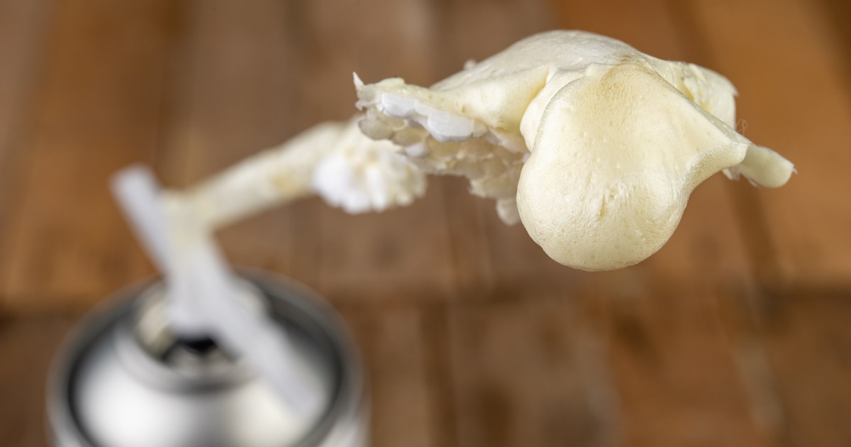 Een spuitbus met PUR-schuim. Het isolatieschuim is licht van kleur en onregelmatig van vorm