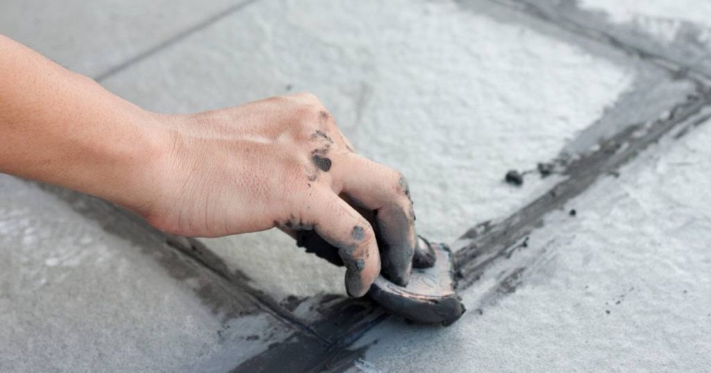Tegels die gebroken worden door door een persoon met cement op de vingers