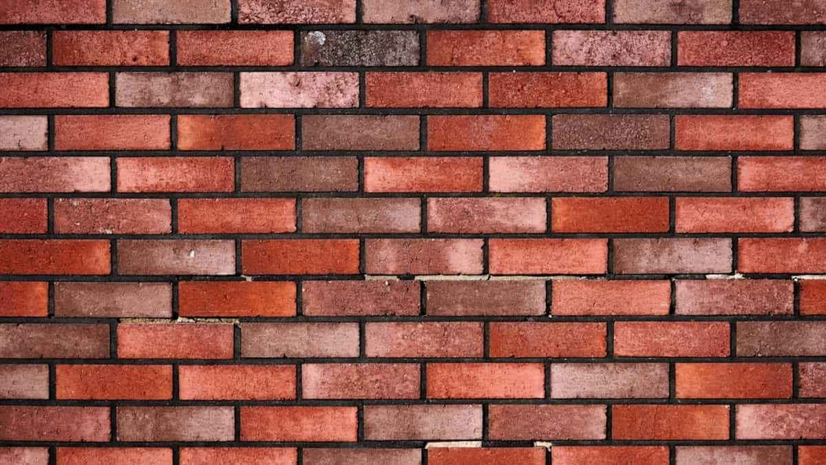 Een muur gemaakt van strengpersbakstenen. De muur is strak en heeft een rode kleur.