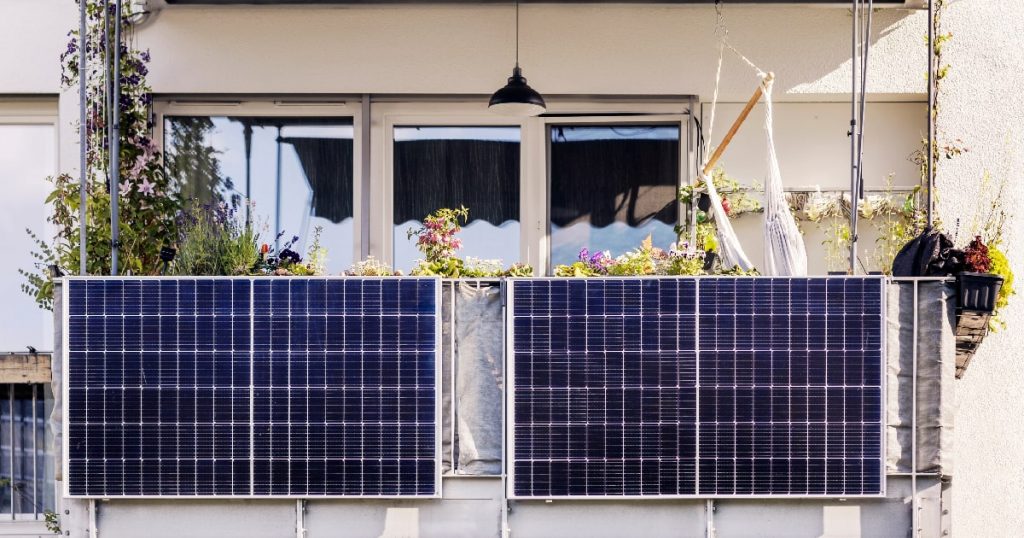 Twee zonnepanelen aan een balkon, aangesloten op de beste thuisbatterij voor een kleine zonnepaneelinstallatie.