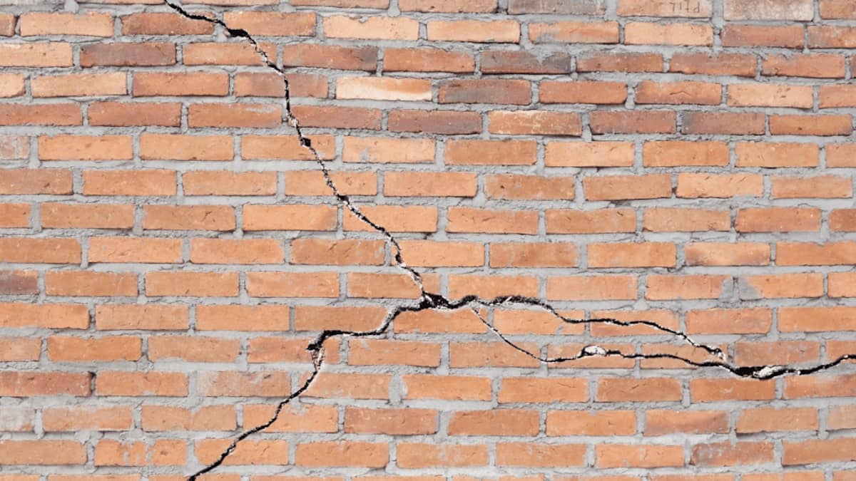 Ernstige constructieve scheuren in de bakstenen gevel van een woning.