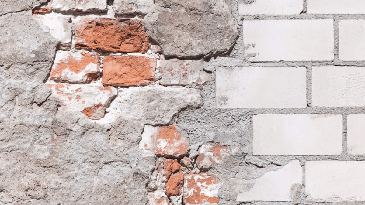 Een bakstenen muur is aan de linkerzijde beschadigd, maar aan de rechterzijde niet. De bakstenen zijn oorspronkelijk rood, maar zijn in een lichte kleur geschilderd.