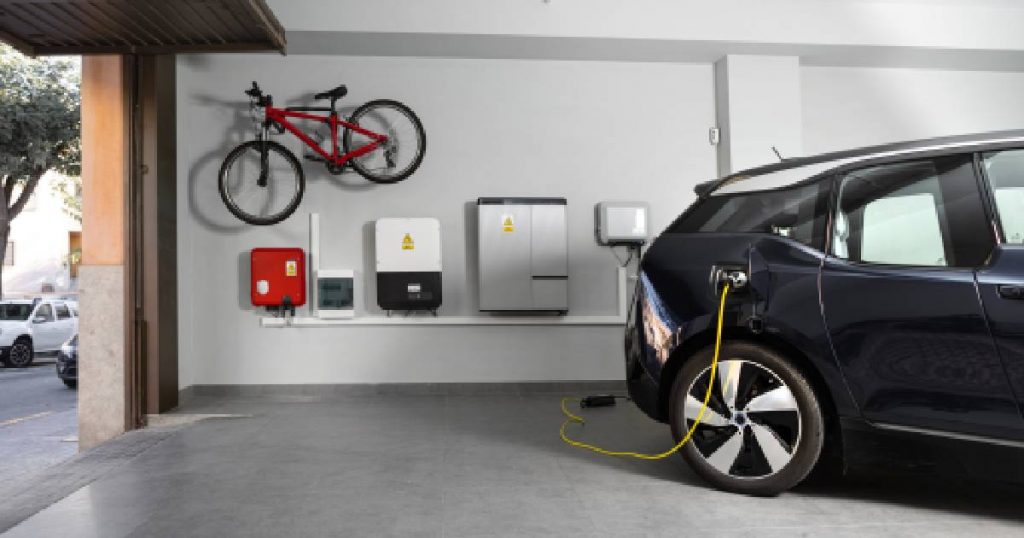 Een zwarte elektrische wagen laadt op in een garage dankzij de thuisbatterij van een woning met zonnepanelen.