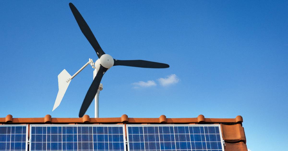 Een oranje pannendak met zonnepanelen en een kleine windturbine.