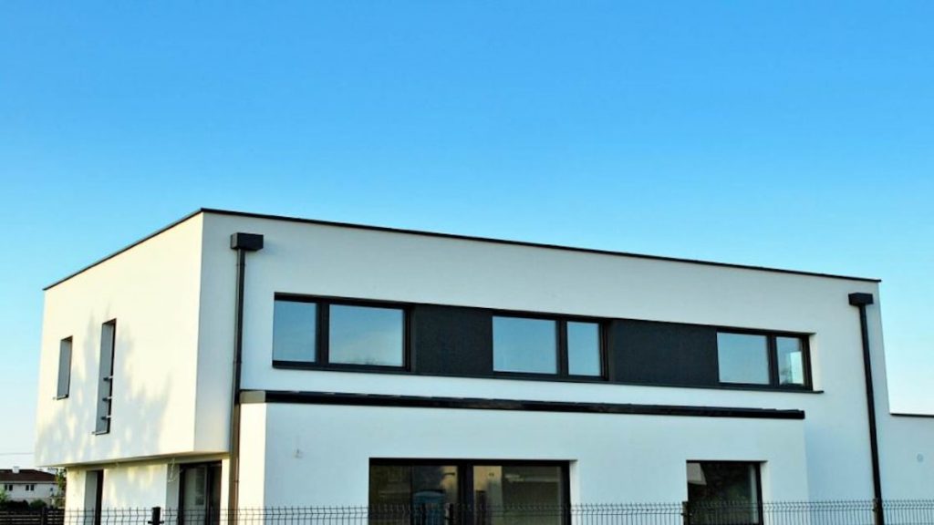 Een moderne woning met een sierpleister gevel in het wit. Tegen de achtergrond is de blauwe lucht te zien.