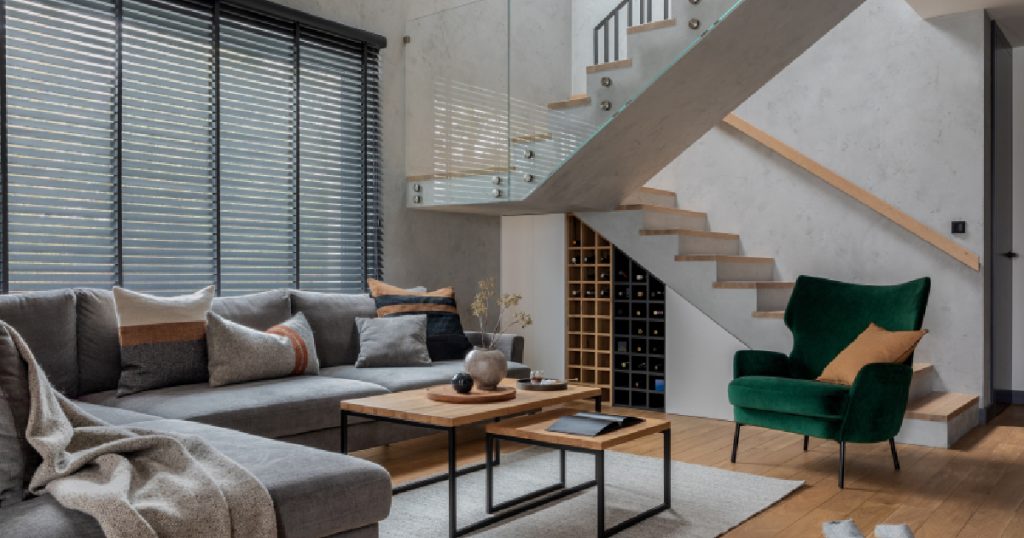Een betonnen kwartslagtrap met bordes. De trap heeft lichte, houten traptreden en een houten trapleuning.