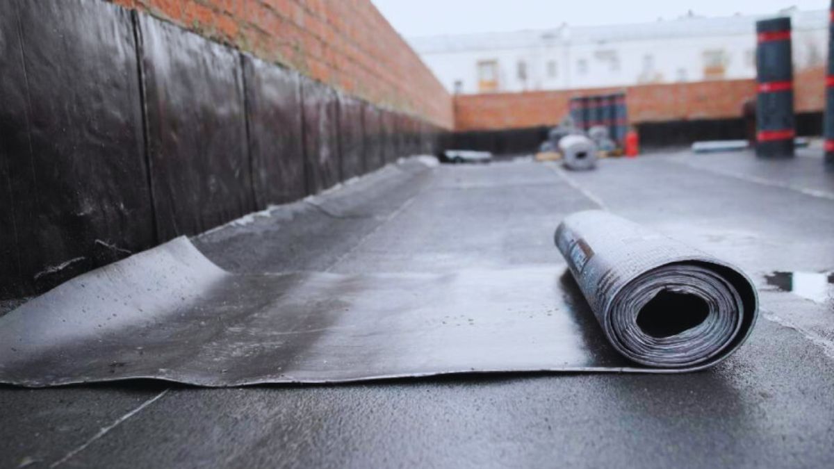 Een half uitgerolde rol bitumen dakbedekking op een dak.