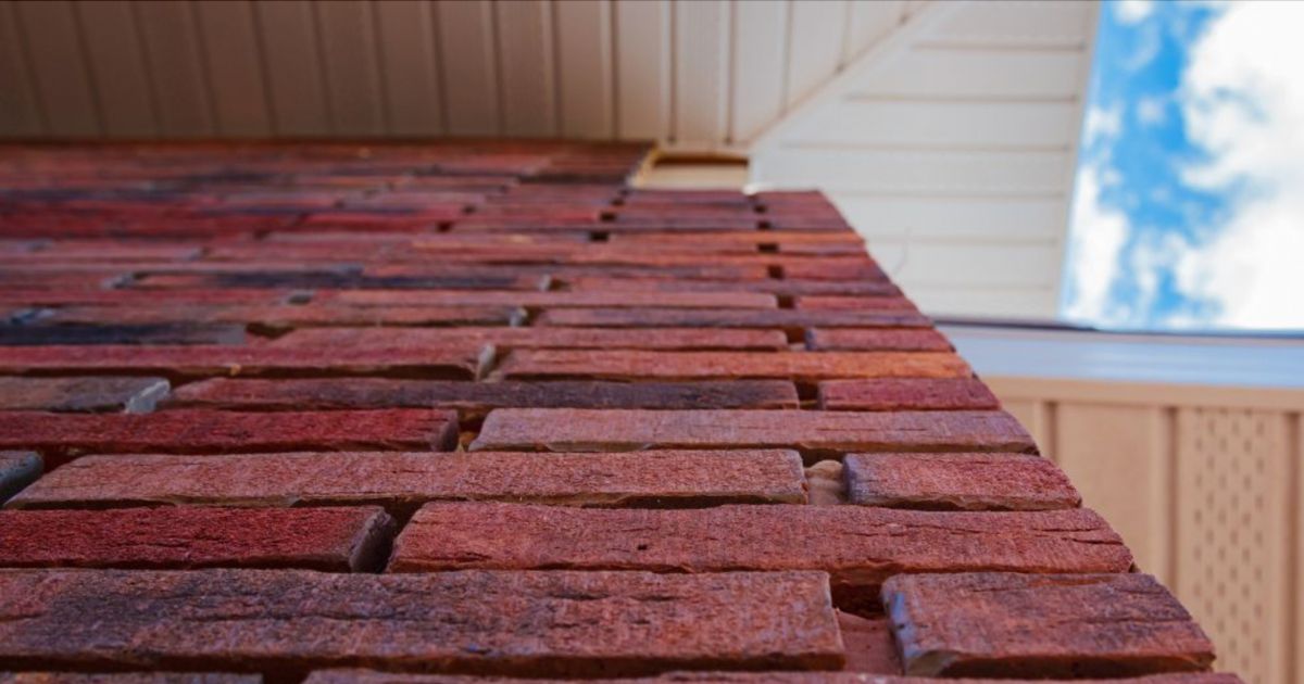 Een buitenmuur is afgewerkt met donkerrode steenstrips